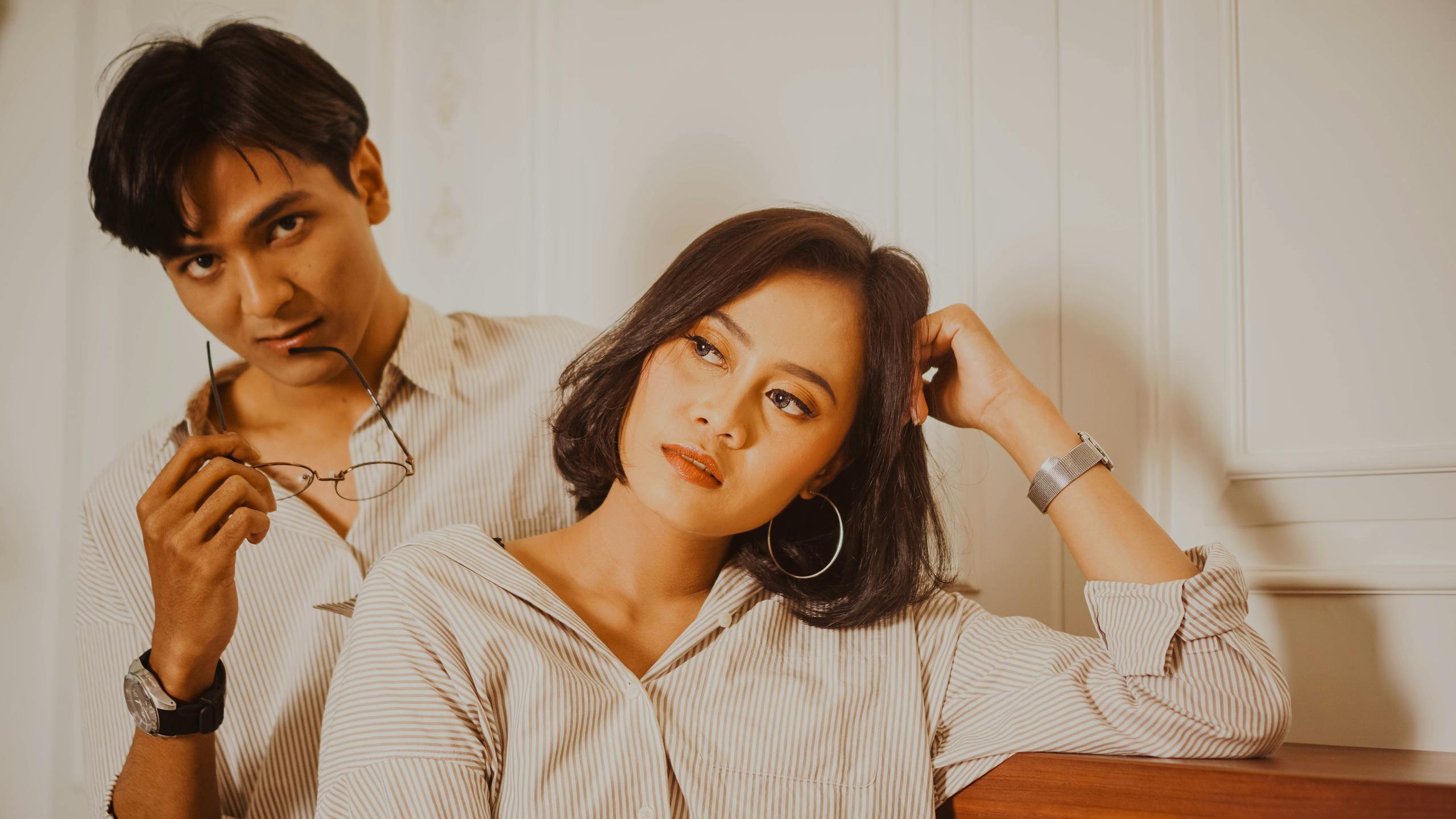 Chic couple in stylish outfits posing indoors, embodying modern fashion and elegance.